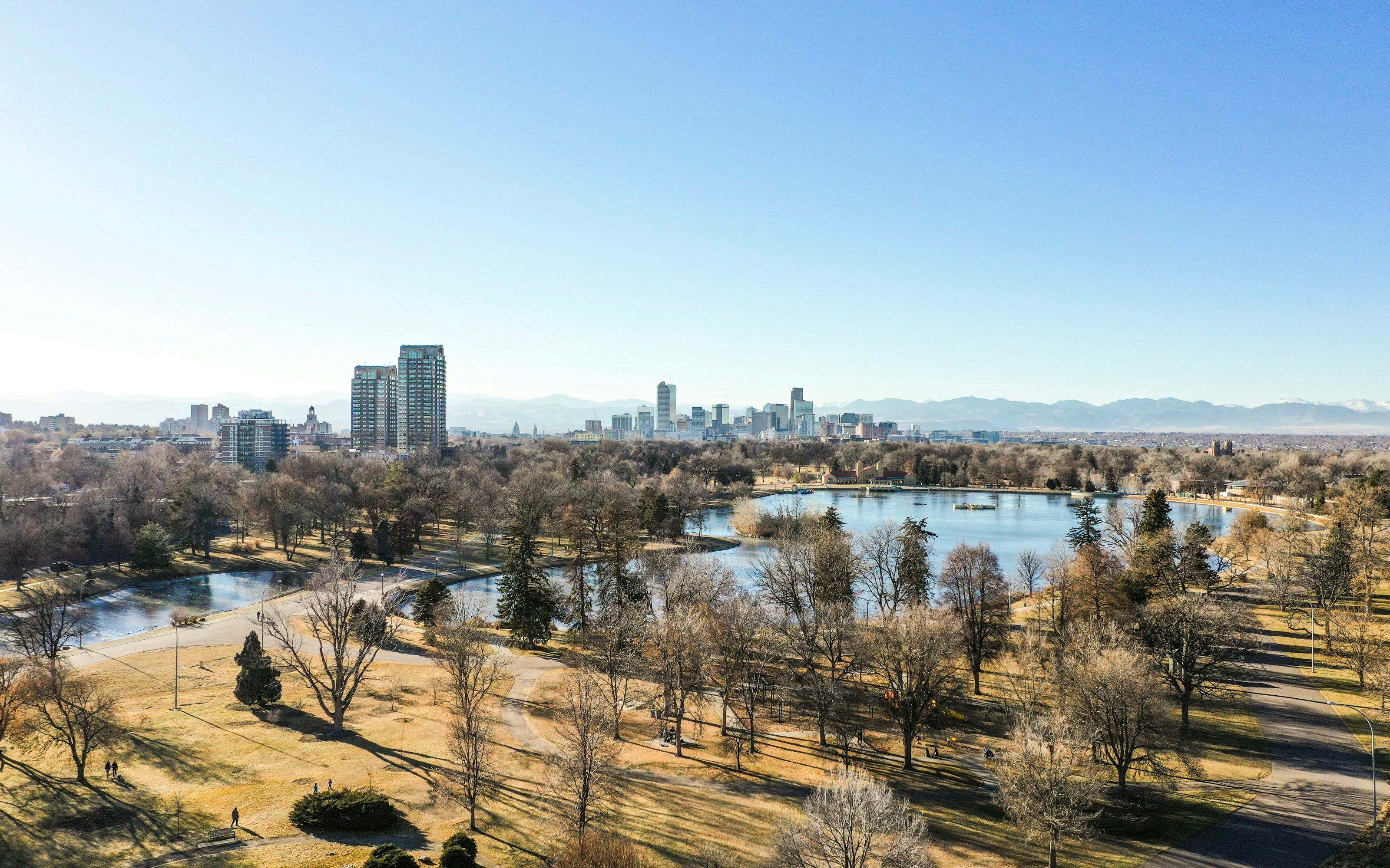 Downtown Denver skyline seen across City Park, with the mountains behind